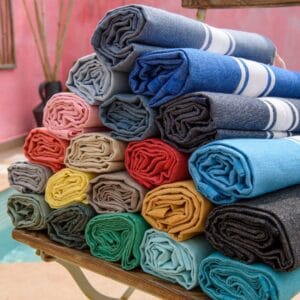 Pirámide de rollos de foutas tunecinas de diferentes colores sobre una silla.