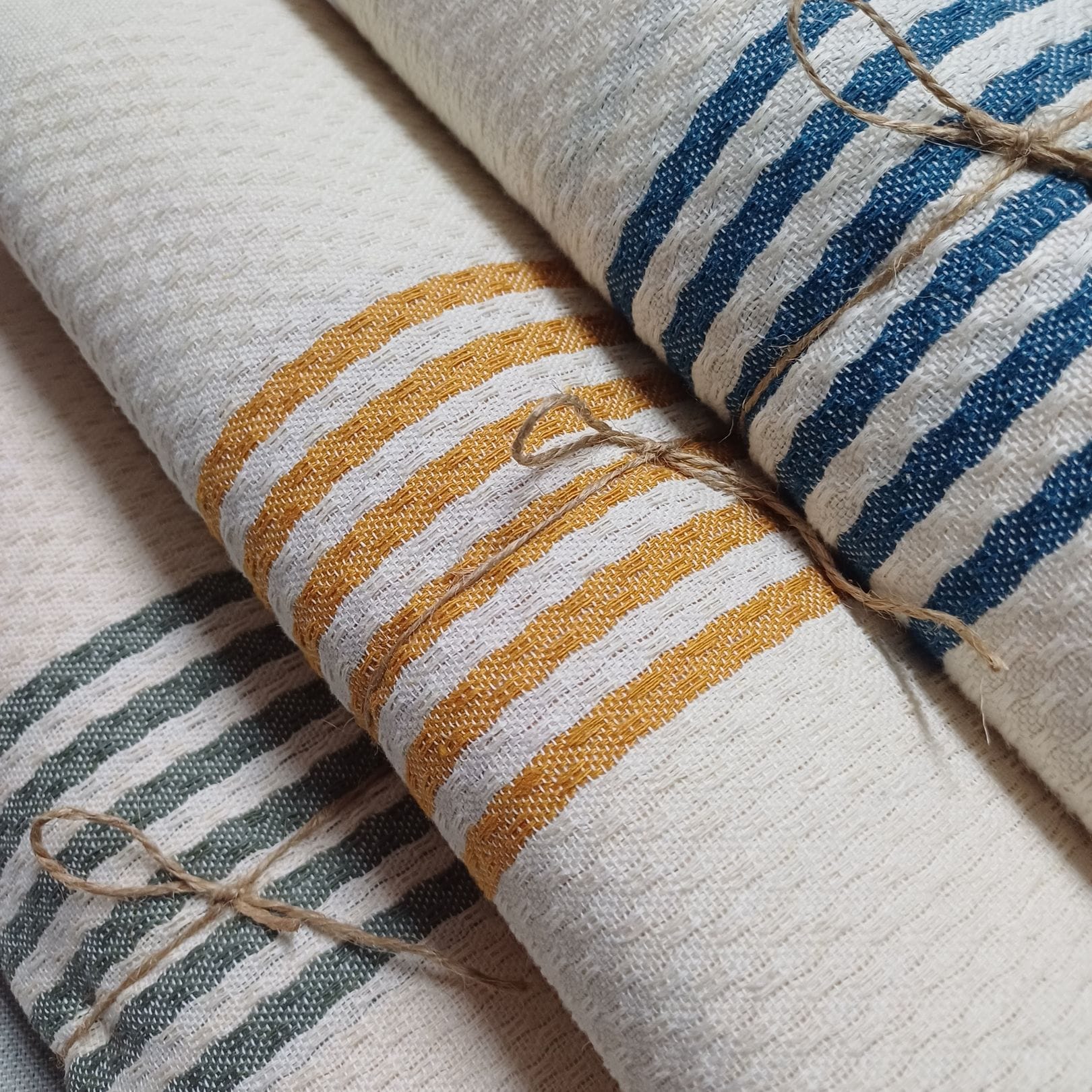 Toallas de baño beige a rayas enrolladas y atadas con una cuerda fina.