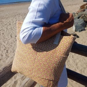 Mujer llevando al hombro un bolso comino y rojo con motivos de diamantes.
