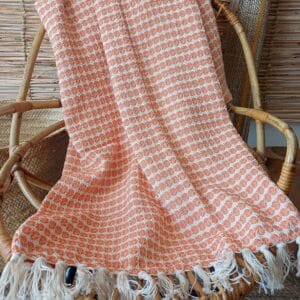 Manta naranja sobre un sillon de ratán