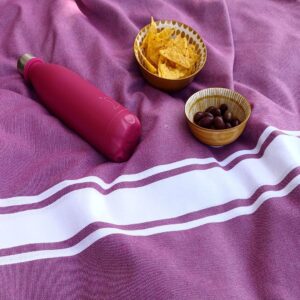 Fouta playa grande en el césped con una cantimplora y unas tapas